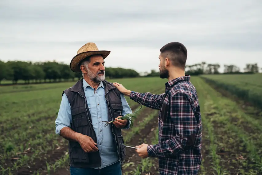 Fermier și specialist Fertillia discutând în câmp, simbolizând parteneriatul pentru performanța agricolă